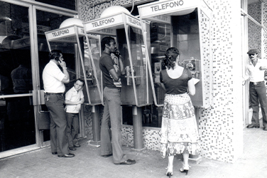 Personas hablando por teléfonos públicos 